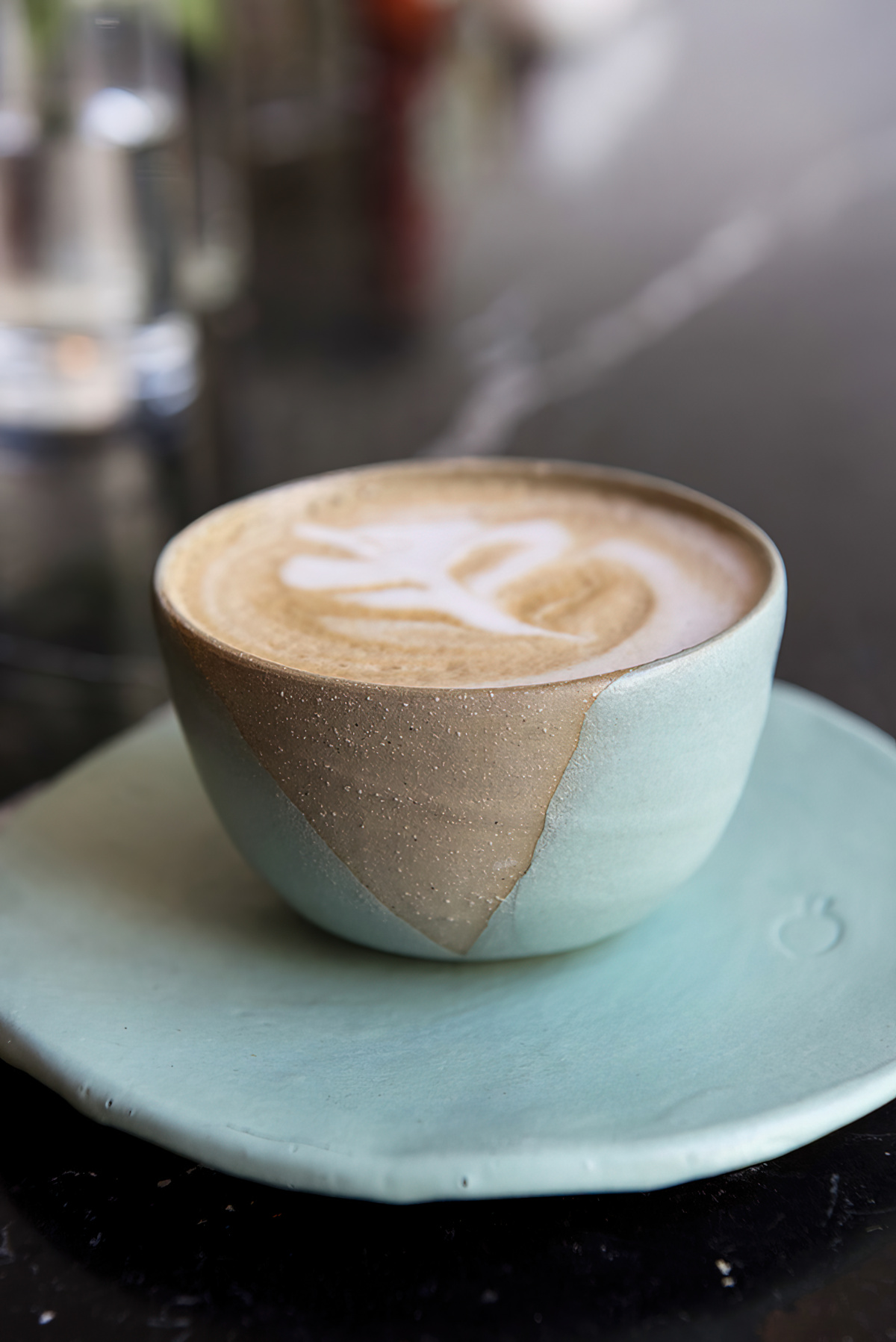 a latte served in a tan and light blue ceramic mug with saucer
