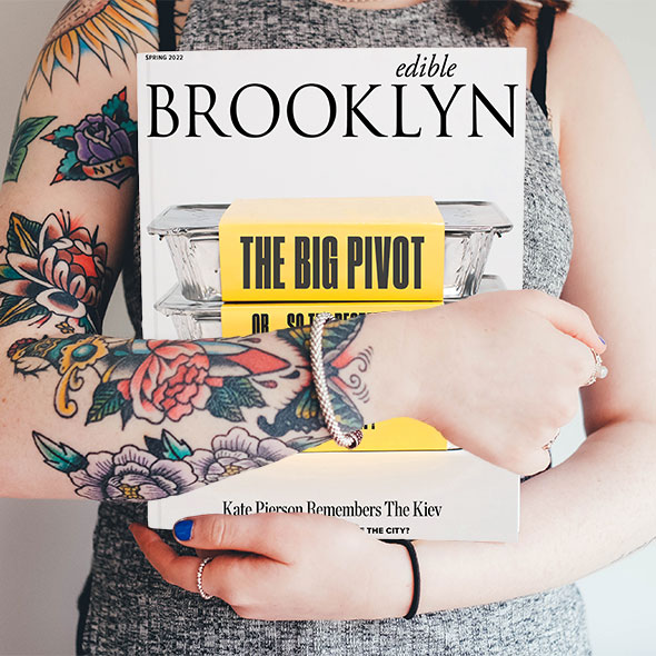 Subscribe_EB_Spr22_PSD_TattooMockup_Crop-590px woman with tattoos holding edible brooklyn magazine