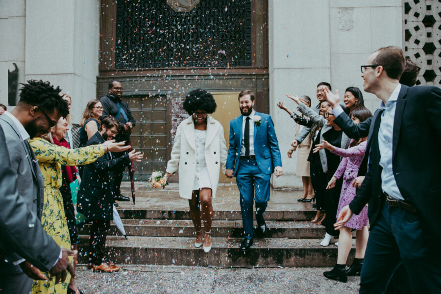 a couple, just married walks through a crowd of wedding attendees throwing confetti
