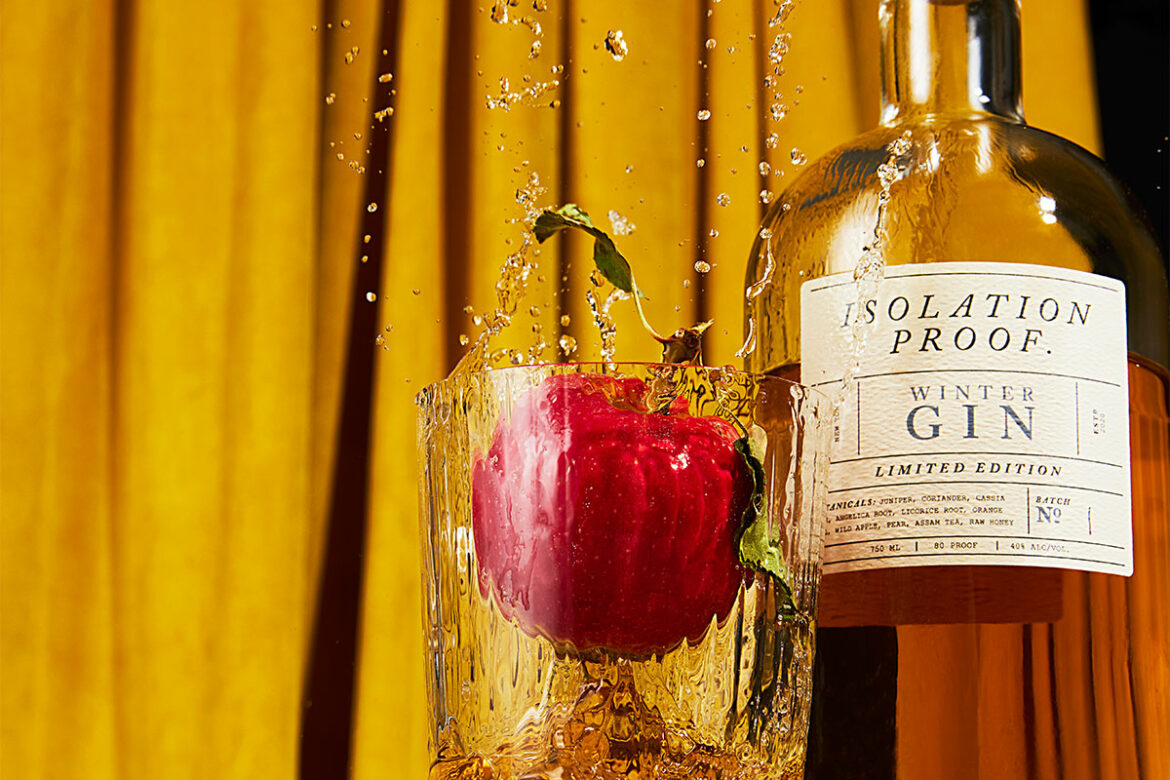 apple splashing into glass of isolation proof gin