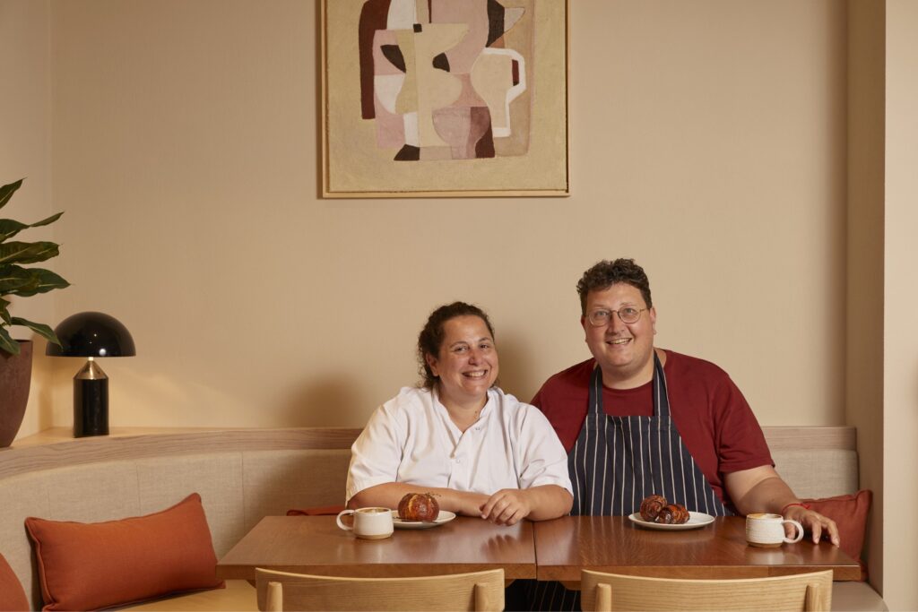 Sarit Packer and Itamar Srulovich sitting at a wood table
