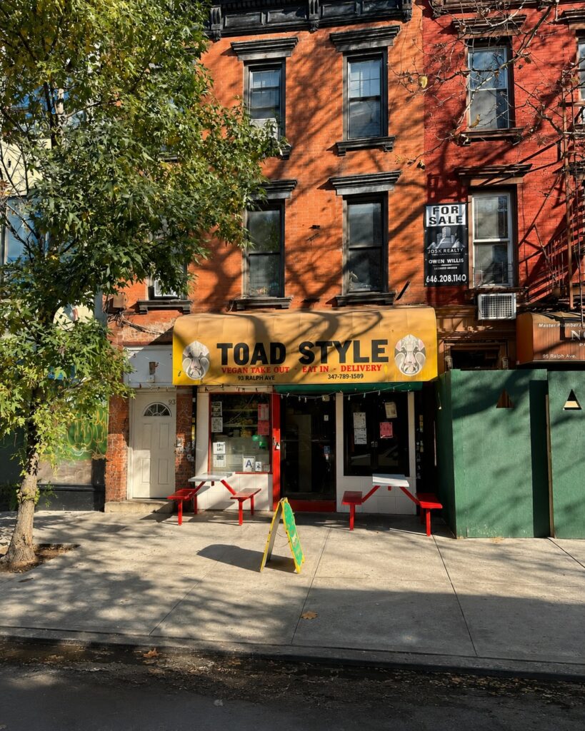 a yellow awning reading toad style on the ground floor of a red brick building with a tree on the left